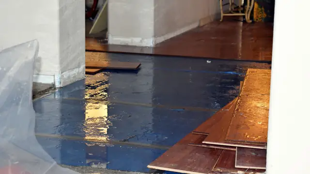 Hardwood floorboards lifted and covered with plastic after water damage