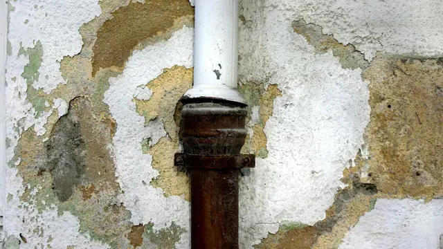Peeling, stained wall around a corroded pipe