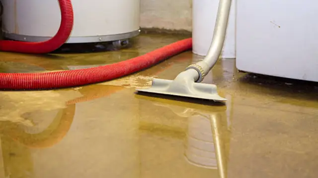 A wet vacuum with a red hose pulling water off a floor